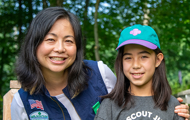a volunteer and girl in girl scout gear smiling